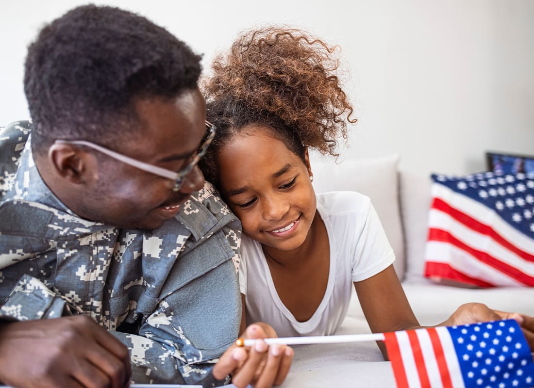 Insurance Solutions - Happy Father in Military Uniform and His Daughter Holding the US Flag